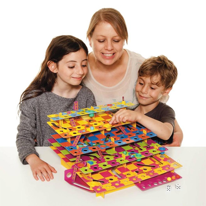 Woman withe 2 children standing over the split-level snakes & ladders game.