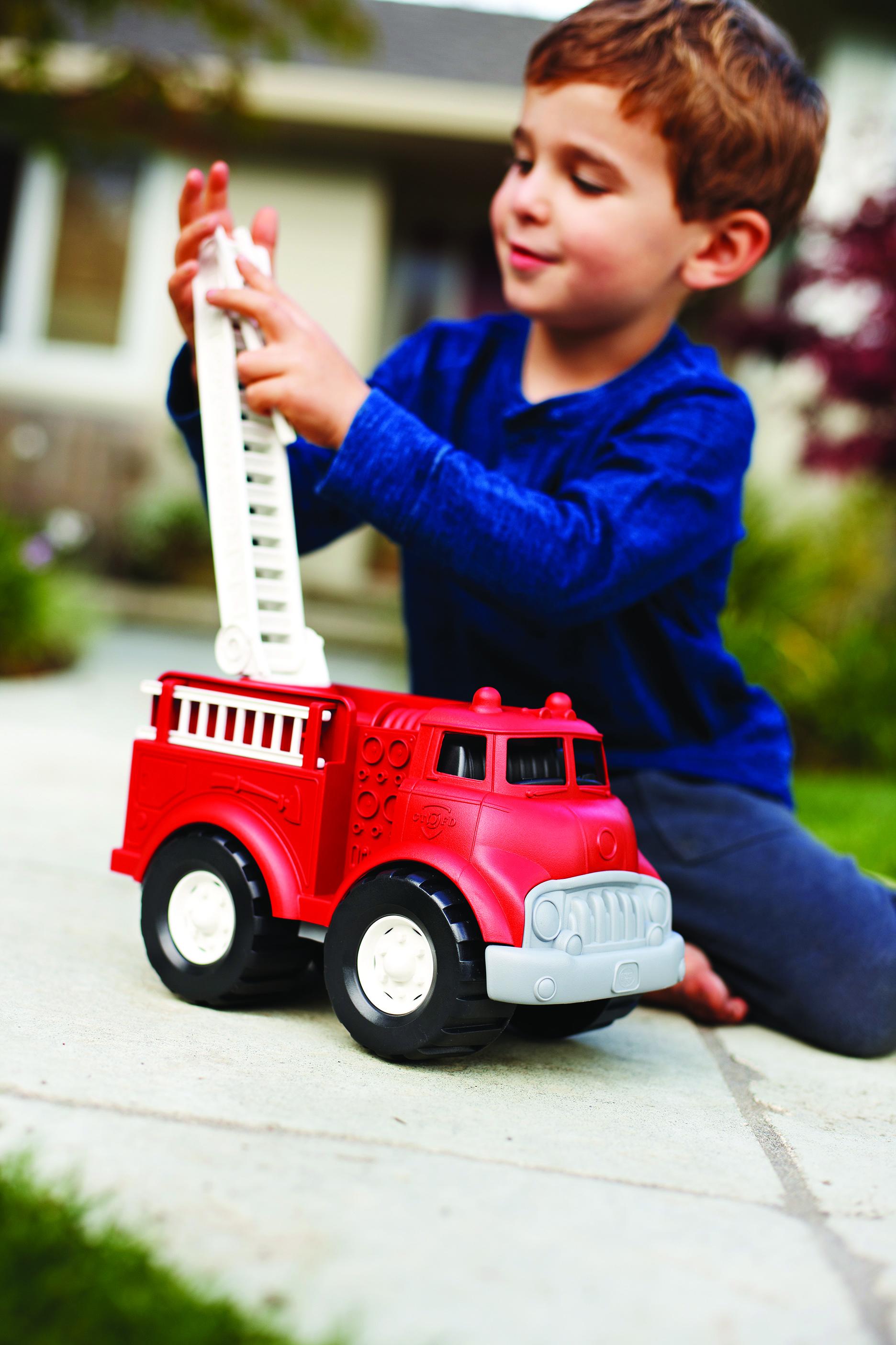 Boy playing with the ladder on red fire engine.