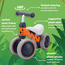The Baby Balance Bike - Benny Tiger by Boldcube is a jungle-themed first birthday gift. It features a cat face design, orange frame, 180° steering with safety limits, carbon steel frame, plush seat, and smooth silent wheels—all set against a green leafy backdrop.
