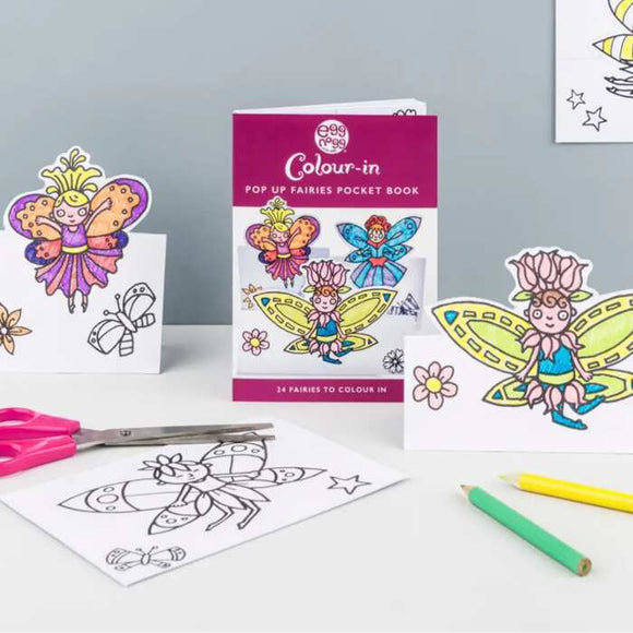 The Card Book - Pop Up Fairies by eggnogg is ideal for kids' parties, offering colored and uncolored fairy cards, colored pencils, scissors, and a "Pop Up Fairies Pocket Book: 24 Fairies to Colour In," all beautifully displayed on a white background.