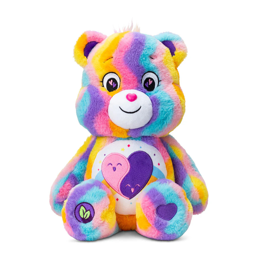 The Care Bears Eco-friendly Friends Forever by Basic Fun features a colorful teddy bear with rainbow fur, a heart design on its belly, embroidered eyes, a smiling expression, and a tuft of white fur on its head. This 35cm bear spreads joy while promoting eco-friendly practices.