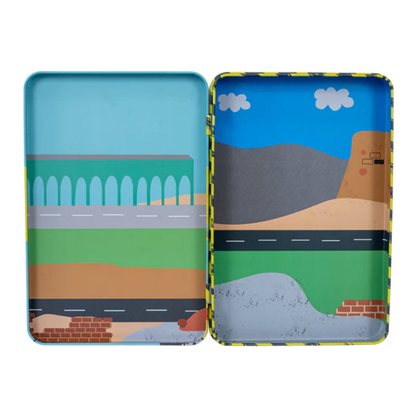 Discover the Construction Magnetic Playtime by Floss & Rock, housed in an open magnetic tin featuring illustrated landscape scenes crafted from recycled materials. The left side showcases a green field with a bridge, while the right side depicts a road leading to mountains under a blue sky. Pop-out magnets enhance each serene view.