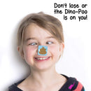 A child with light brown hair grins while crossing their eyes to look at a Dino Dump sticker on their nose. Text at the top right says, "Don't lose or the Dino-Poo is on you!" It's all part of Big Potato's hilarious dinosaur card game that fits perfectly as a travel-size game for endless fun.