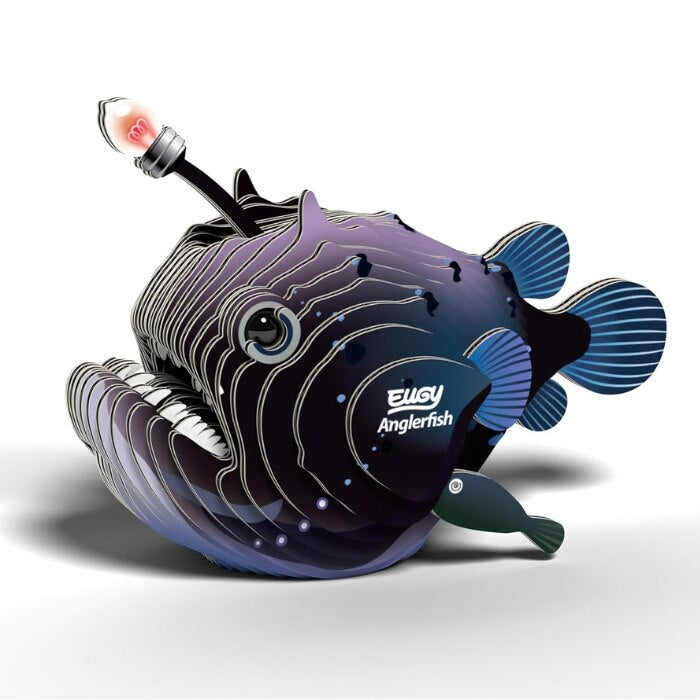 A digital illustration of an anglerfish with a glowing lure showcases its stylized, layered body in shades of blue and purple, reminiscent of the EUGY Anglerfish figures. The word "Anglerfish" is prominently inscribed on its side, inviting you to craft your way into the depths of creative imagination under the esteemed EUGY brand.