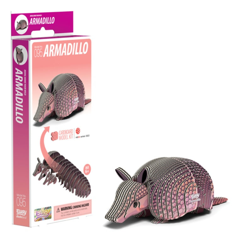 The EUGY Armadillo 3D cardboard model kit is crafted from sustainable materials. The pink and white box, labeled "Armadillo #056," displays the assembled armadillo and features award symbols, a choking hazard warning, and a note about non-toxic glue.