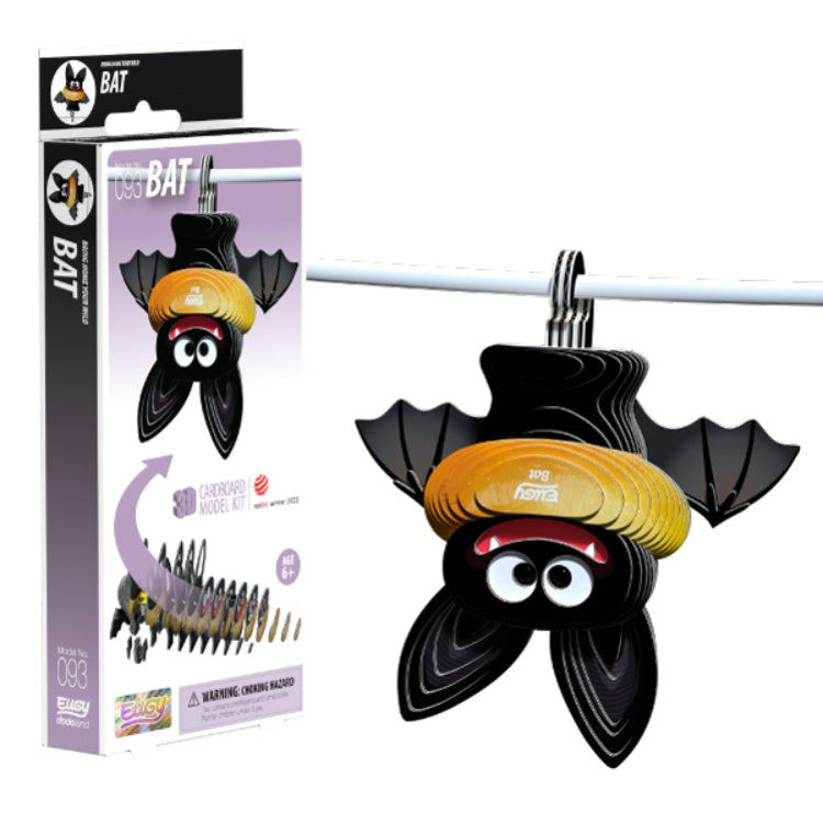 The EUGY Bat, a fun and eco-friendly craft model from the brand EUGY, hangs upside down on a line. Its packaging showcases a cartoon bat with big eyes and a yellow-striped hat, highlighting its sustainable design. This craft item is designed for easy assembly, encouraging creativity with environmentally friendly materials.