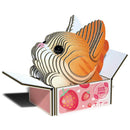 The Eugy Cat - Pumpkin by EUGY is a delightful 3D cardboard model depicting an orange and white cat with large eyes, nestled inside an open, decorated box made from recyclable card. The box features strawberry designs and "100% organic" printed on the side, making it a perfect collectible piece.