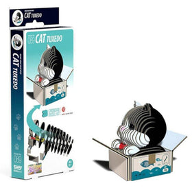 Introducing the "Eugy Cat - Tuxedo" by EUGY, a cardboard model kit that creates an eco-friendly 3D figure of a cat in a tuxedo pattern sitting inside a box. The packaging highlights the completed model along with various items adorning the box's surface, making it an ideal choice for fans of collectible miniature figures.