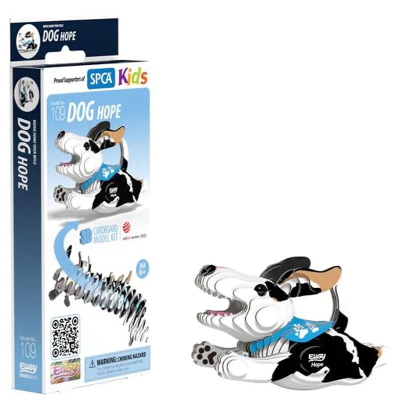 The "EUGY Dog - Hope" cardboard model kit package features an illustration of a cartoon dog in black and white, made with eco-friendly ink. Recommended for ages 6 and up, it is produced by EUGY using recyclable card material. The completed miniature 3D dog figure is showcased next to the package.