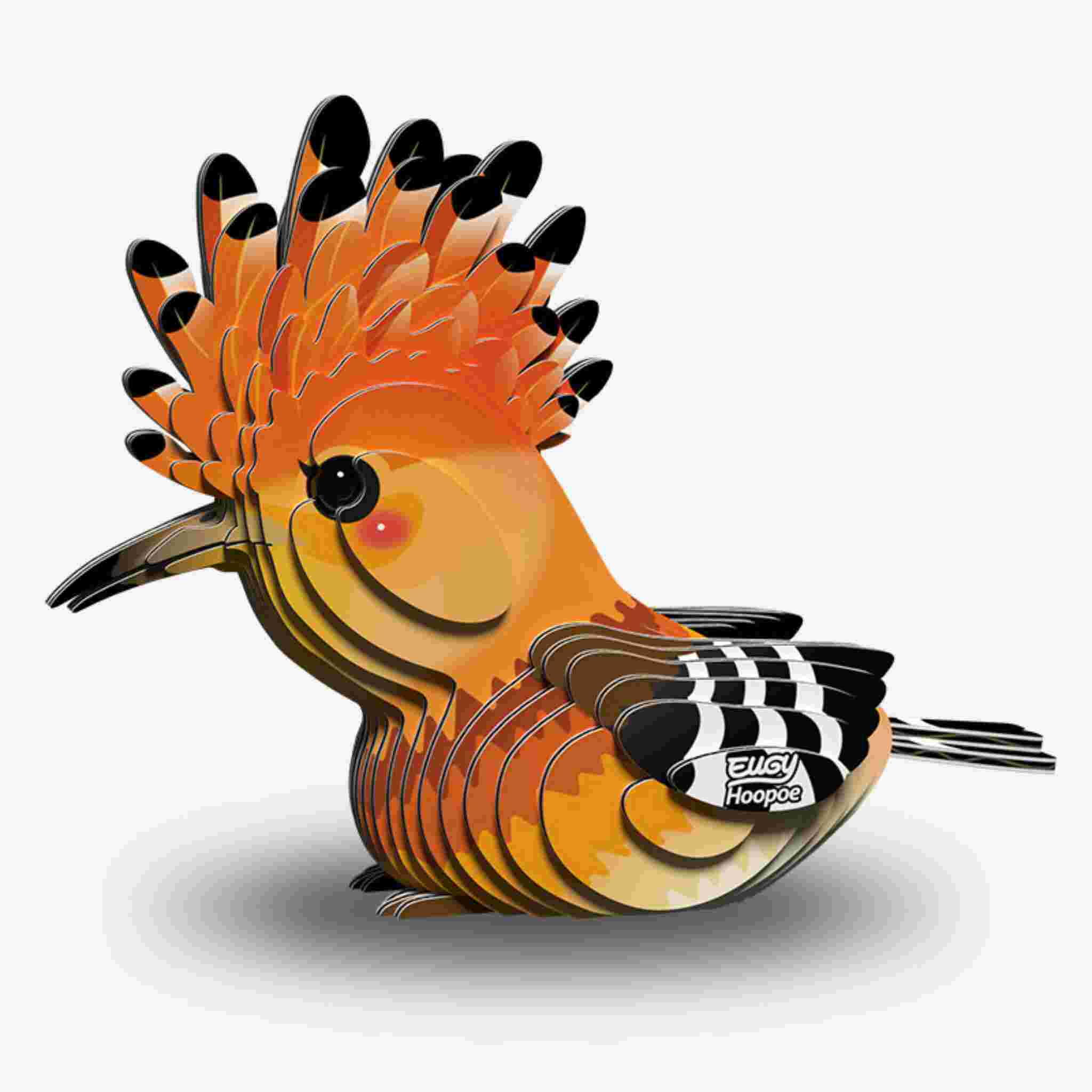 Illustration of an orange cartoon bird with a black-tipped crest, rounded body, and striped tail in layered paper art for a 3D effect. The bird resembles EUGY figures, faces left, and features the word "EUGY Hoopoe" on its body.