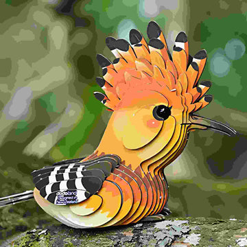The EUGY Hoope is a colorful, ornate bird sculpture depicting a hoopoe perched on a branch. It features bright orange and yellow plumage with black and white-striped wings set against a blurred green background that suggests a forest or garden full of insects.