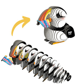 The EUGY Puffin, by the brand EUGY, is an eco-friendly sculpture crafted from sustainable, colorful wooden layers. The separate layers are displayed at the bottom, leading up to the finished Puffin at the top. An arrow illustrates the transformation from individual pieces to a complete sculpture.