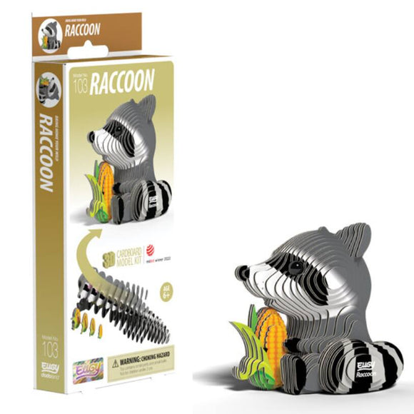 The EUGY Raccoon model kit, featuring an eco-friendly cardboard raccoon next to a corn cob, is presented beautifully. The packaging to the left provides assembly instructions and highlights the 3D collectible raccoon model. Ideal for children aged 6 and up, this kit from EUGY guarantees hours of imaginative fun.
