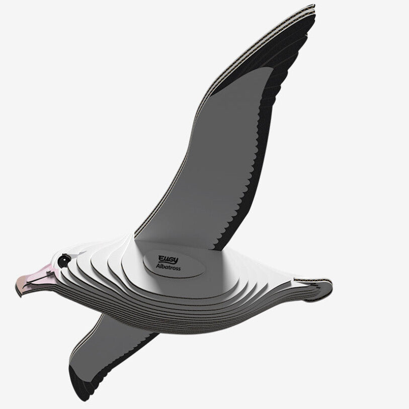 Illustration of the EUGY Royal Albatross in flight, designed as a layered, three-dimensional puzzle crafted with eco-friendly inks. The bird is primarily gray and white, featuring text on its body that reads "Easy Albatross.