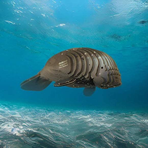 The EUGY Manatee, by EUGY, is a robotic sea creature resembling a marine animal. Its sleek black and metallic segmented body glides gracefully through blue ocean waters, promoting conservation with its eco-friendly design.