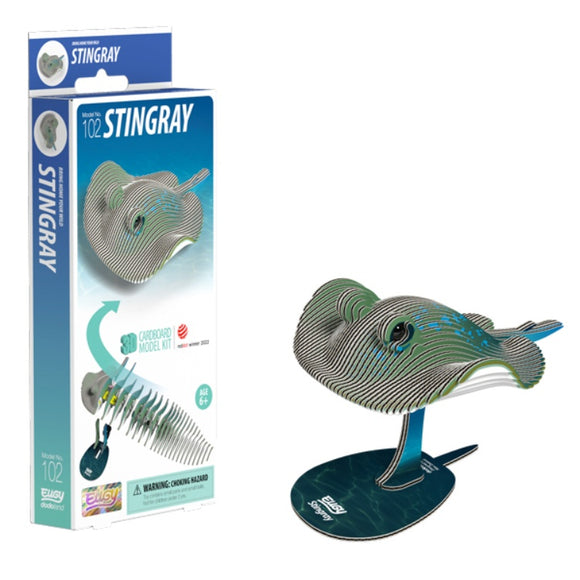 The packaging and assembled view of the EUGY Stingray model kit made from eco-friendly cardboard is on display. The box on the left features an image of the stingray along with its attributes, while the assembled model on the right emphasizes its sustainable materials in a layered design mounted on a stand.