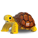 The EUGY Tortoise is a 3D puzzle model crafted from eco-friendly materials, showcasing a cartoonish design with yellow and brown sections. "EUGY Tortoise" is printed on its shell, and it features striped patterns on its body along with large, expressive eyes that enhance its charming appeal.