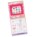 An open coloring book titled "Fantasy Paint by Numbers" from Floss & Rock showcases a whimsical scene with a fairy, pink flamingo, and unicorns amid stars and clouds. Above the scene is a palette of vibrant star-shaped paints, while a purple pencil lies on the eco-friendly pages, inspiring creativity in this imaginative adventure.