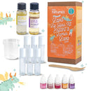 The DIY Natural Lava Lip Gloss Kit by KISS NATURALS is showcased with a variety of components, all crafted from all-natural ingredients. The kit includes bottles of sunflower and castor oil, a mixing cup, a wooden stir stick, several empty lip gloss tubes, and small bottles of colorant. The backdrop features whimsical dragon illustrations.
