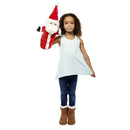 A young girl dressed in a light blue sleeveless top, jeans, and brown boots is holding a Santa Long Sleeved Puppet by The Puppet Company Ltd with her right hand. She stands against a plain white background, smiling brightly.
