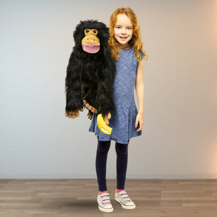 Young girl holding a plush monkey puppet toy against a plain background