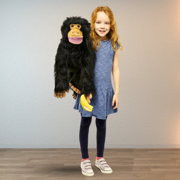 Young girl holding a plush monkey puppet toy against a plain background