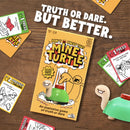 The Toy Shop's "Mine Turtle" board game, with its explosive twist on the classic Truth or Dare, sits on a wooden table surrounded by cards and a turtle figurine. The text says, "Truth or Dare. But Better.