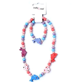 The Dolphin Bead Necklace & Bracelet Set by molly & rose features vibrant beads in pink, blue, and purple with pearl bead accents. Each piece showcases adorable dolphin charms and fish-shaped beads, all displayed on a white background with the "molly & rose" tag.