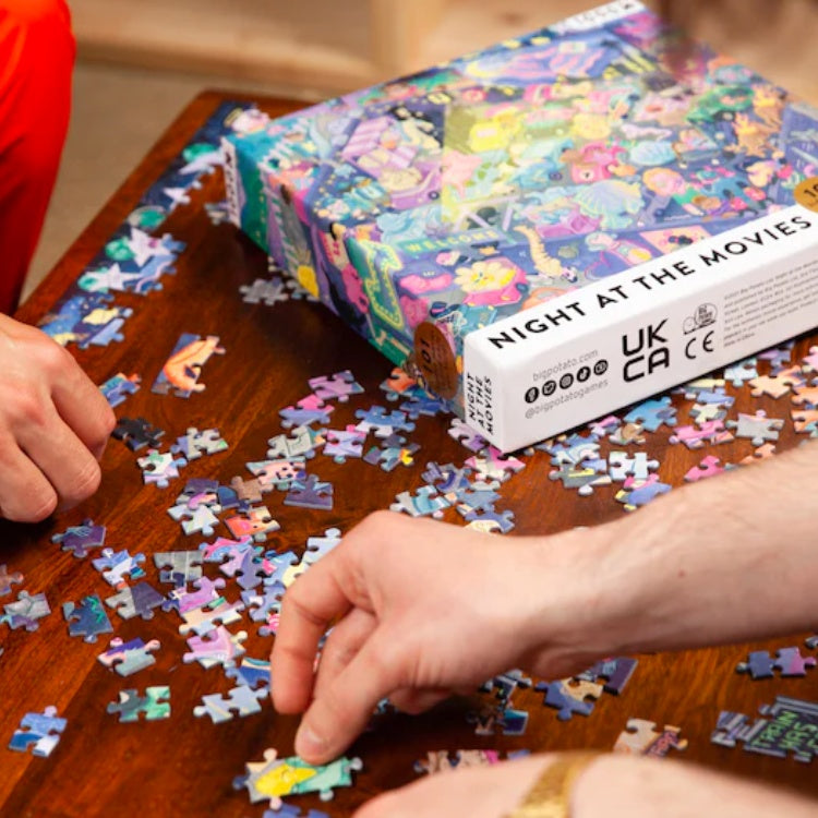 Hands placing pieces of the jigsaw on a wooden table.