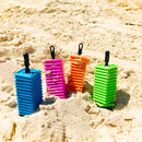 Blue, pink , orange and green plastic tiles stacked on a holder - all resting in sand.