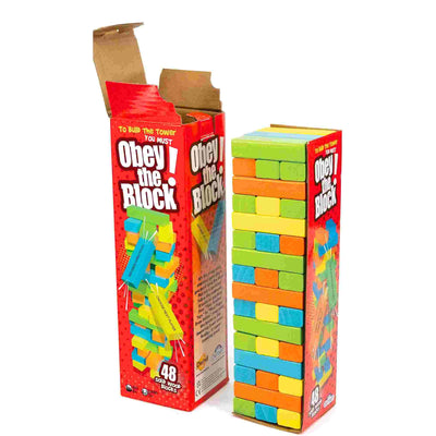 The Outset Media Obey The Block stacking game is shown with its box open, revealing 48 solid wood blocks in green, blue, yellow, and orange neatly stacked next to the packaging—ideal for building a wobbly tower.