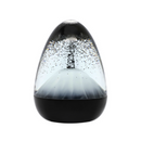 The Sensory Motion Egg Volcano, on a sleek dark base, showcases swirling dark crystals inside its egg shape against a plain white backdrop, making it an ideal stress-relief fidget toy.
