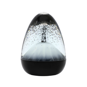 The Sensory Motion Egg Volcano, on a sleek dark base, showcases swirling dark crystals inside its egg shape against a plain white backdrop, making it an ideal stress-relief fidget toy.