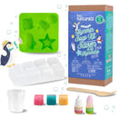 The DIY Natural Glycerin Soap Kit by KISS NATURALS includes a green silicone mold with various shapes, white soap blocks, three colorful soap samples, a small measuring cup, a wooden stick, and two bottles of coloring or scent. The packaging prominently displays the brand and product information.