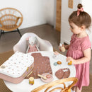 Child playing with toys at a table in a room with a chair and doll.