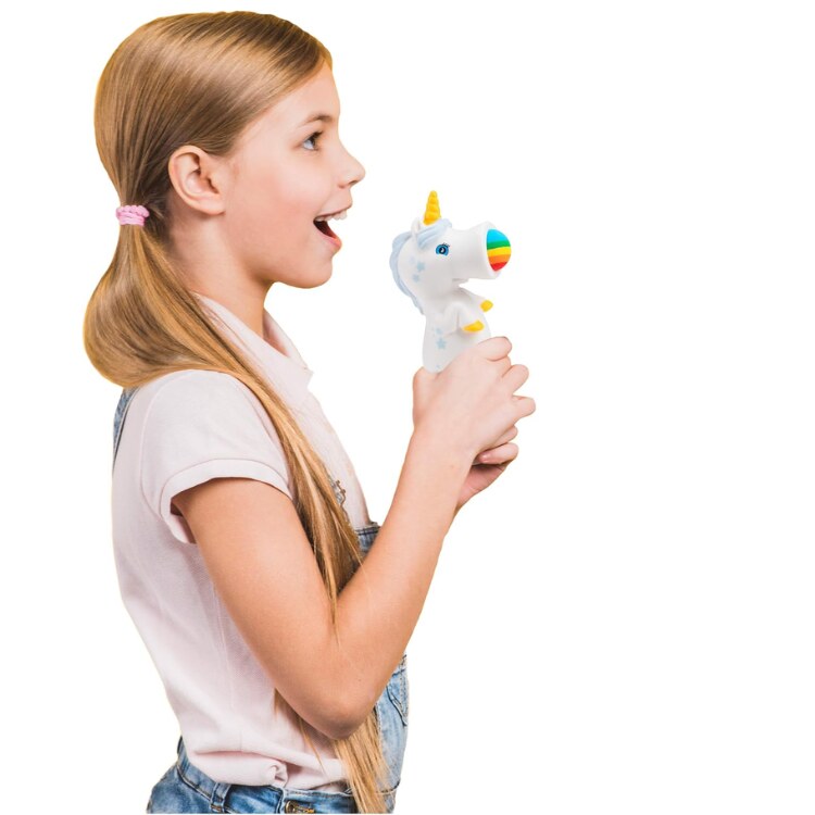 A young girl with long blonde hair enthusiastically holds a Squeeze Popper: Unicorn White from Cheatwell Games, an air-powered toy that projects a rainbow light. She faces right against a white background, exuding excitement. Wearing a pink t-shirt and denim overalls, she looks like she's stepped right out of the latest Squeeze Poppers collection.