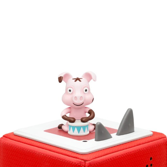 A small, pink cartoon figure resembling a pig sits on a red platform. With a cheerful expression, it's holding a drum, ready to lead children's music. The platform has two gray, triangular shapes beside the figure, inviting kids to sing along to fun animal-themed songs from the Tonie - Favourite Children's Songs - Animal Songs by Tonies.