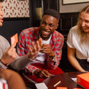 Three adults laughing while playing the Weird Things Humans Search For game.