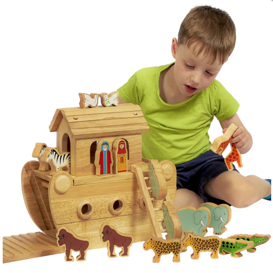 A young boy in a green shirt enjoys Lanka Kade's Junior Noah's Ark with Colourful Characters, featuring eco-friendly animal figures like zebras, lions, elephants, giraffes, and two humans. The handcrafted Ark includes a ramp for added play fun.