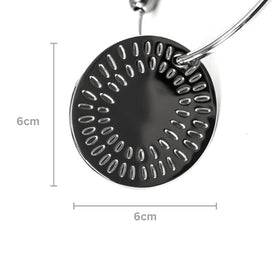 A round, metallic object with a symmetrical pattern of oval holes, similar to Yummikeys. This piece, part of a handle loop by YUMMIKEYS' Stainless Steel Woodland Teething Keys, measures 6 cm in diameter as indicated by measurement lines on the image.