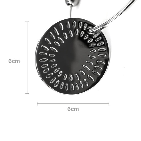 A round, metallic object with a symmetrical pattern of oval holes, similar to Yummikeys. This piece, part of a handle loop by YUMMIKEYS' Stainless Steel Woodland Teething Keys, measures 6 cm in diameter as indicated by measurement lines on the image.