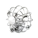 The YUMMIKEYS Yummirattle is a stainless steel wire sculpture designed like an atom, featuring a central sphere with surrounding spheres linked by curved rods. Its shiny, intricate design aids in motor skills development and functions as a unique baby rattle.