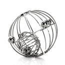 The Yummikeys - Yummirattle by YUMMIKEYS is a stainless steel rattle featuring multiple spherical beads and intersecting wires that form a sphere. Its design aids motor skills development and casts intricate shadows on a white surface.