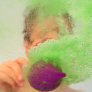 Someone holding a Zimpli Kids Baff Bombz Magic Brush is surrounded by vibrant, fizzing green bubbles in the water, creating an enchanting and dynamic bath experience with biodegradable bubbles.