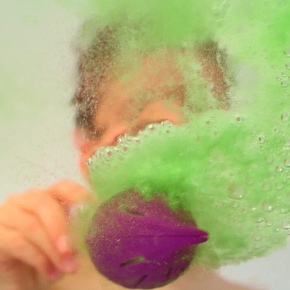 Someone holding a Zimpli Kids Baff Bombz Magic Brush is surrounded by vibrant, fizzing green bubbles in the water, creating an enchanting and dynamic bath experience with biodegradable bubbles.