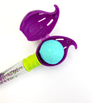 Zimpli Kids' Baff Bombz Magic Brush features a clear wand filled with colorful glitter, topped with a purple leaf-shaped case. Inside awaits a turquoise bath bomb for biodegradable fizzing fun, offering a magical bathtime experience.