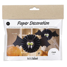 The Mini Craft Kit Paper Decorations, Bat by Creativ Company includes a DIY set to make two black bats with green eyes. Perfect for ages 5 and up, the background displays a room decorated with similar bats.
