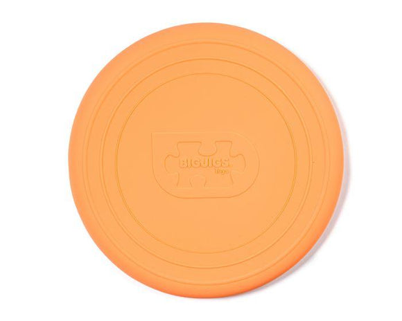 Bright orange Foldable Flyers from The Toy Shop feature a circular, grooved design. This eco-friendly silicone toy showcases an embossed logo with "BIGJIGS" inscribed over a puzzle piece at its center.