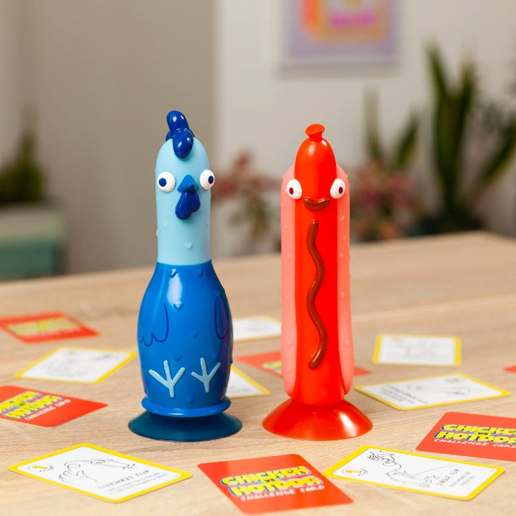 Comical, blue tubular plastic hen with a suctioned base beside a red plastic hot dog with a suction base. 