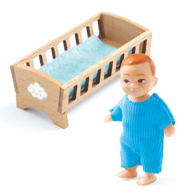 Introducing the Dolls' House - Baby Sacha from Djeco: a charming small toy doll with short brown hair, dressed in a vibrant blue onesie. Accompanying it is a delightful wooden toy crib complete with a blue mattress. The crib features intricate cut-out slats and cloud decorations, making it an ideal addition to any dolls' house nursery.